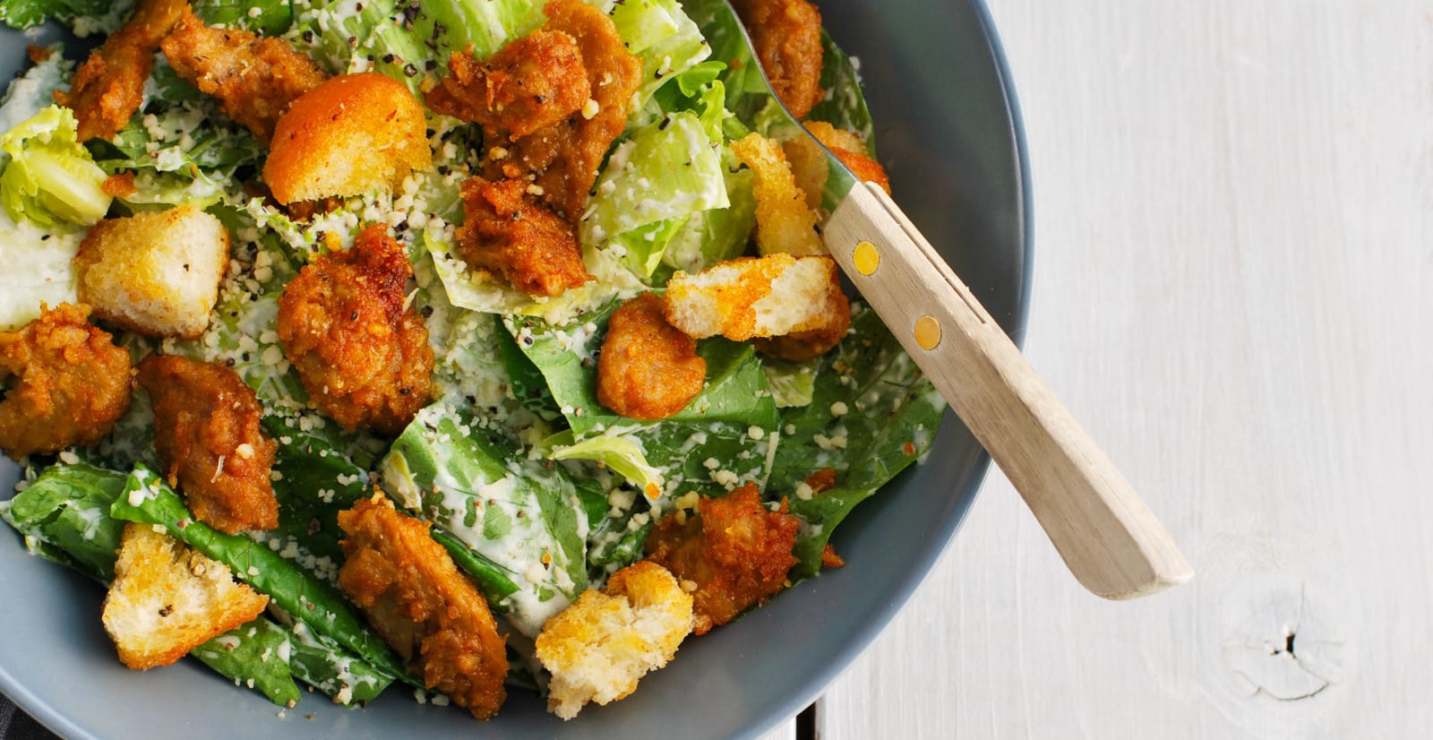 Caesarsalaatti vegekanalla harmaalla lautasella