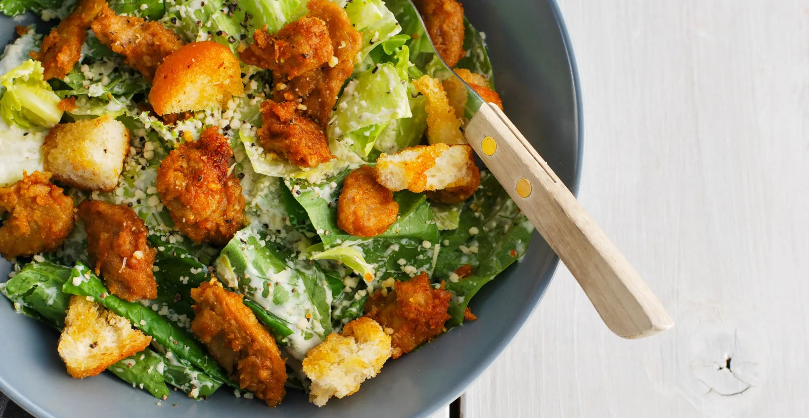 Caesarsalaatti vegekanalla harmaalla lautasella